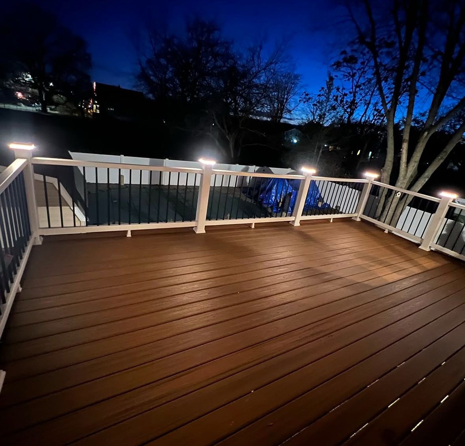 The same deck lit at night with post cap lighting